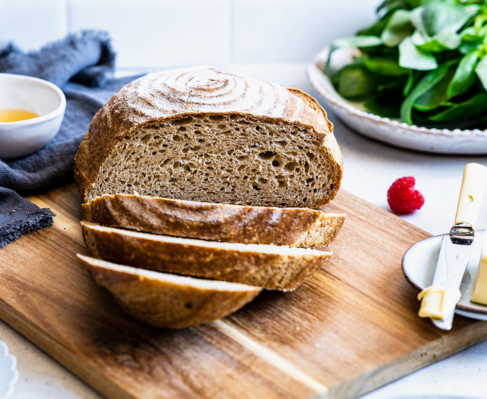 Un pain boule sans gluten de chez Piaf Gluten Free déposé sur une planche en bois et coupé en tranches